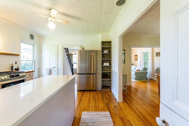 21 Elm St, Belfast, ME 04915 - kitchen featuring appliances with stainless steel finishes, light wood-style flooring, tasteful backsplash, ceiling fan, and light countertops