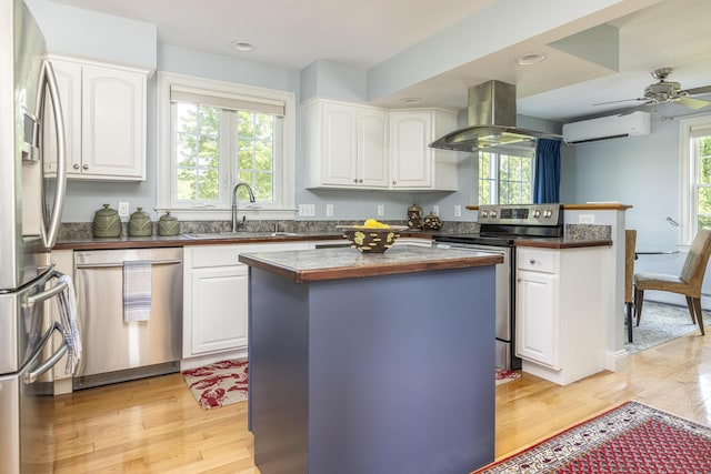 86 Allison Ave, Portland, ME 04103 - kitchen with stainless steel appliances, island range hood, a wall unit AC, light wood-style floors, and a peninsula