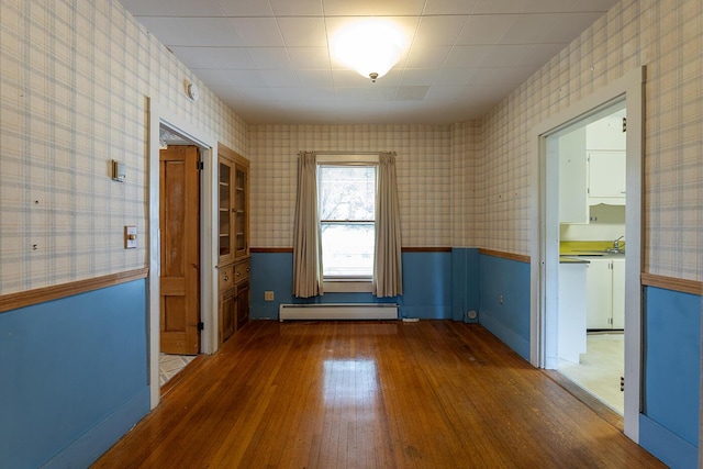 131 Russell Ave, Rockport, ME 04856 - spare room with a baseboard radiator, wallpapered walls, wood finished floors, and a wainscoted wall