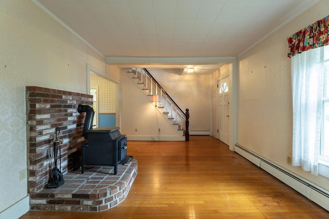 131 Russell Ave, Rockport, ME 04856 - living area featuring a baseboard radiator, a wood stove, wood finished floors, crown molding, and stairs