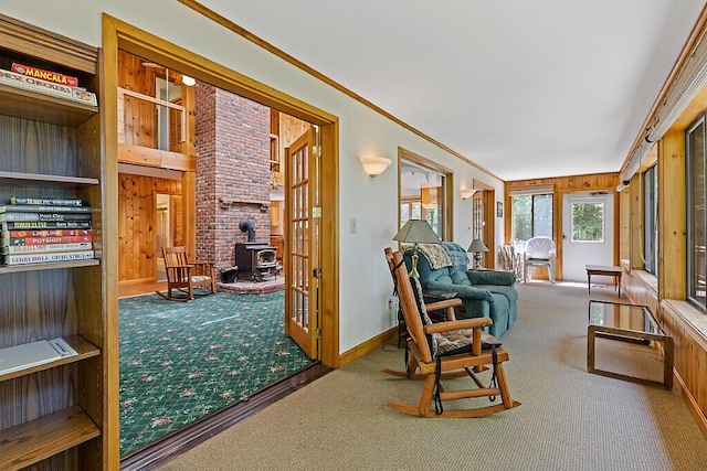 176 Perkins Beach Rd, Wayne, ME 04284 - sunroom featuring carpet floors, a wood stove, crown molding, and wooden walls