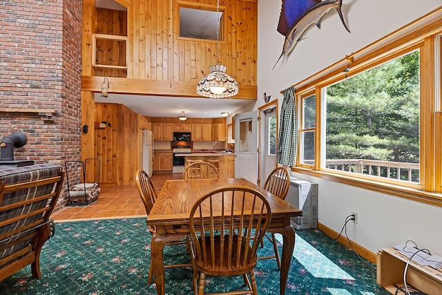 176 Perkins Beach Rd, Wayne, ME 04284 - dining room featuring wooden walls, a towering ceiling, and light tile patterned floors
