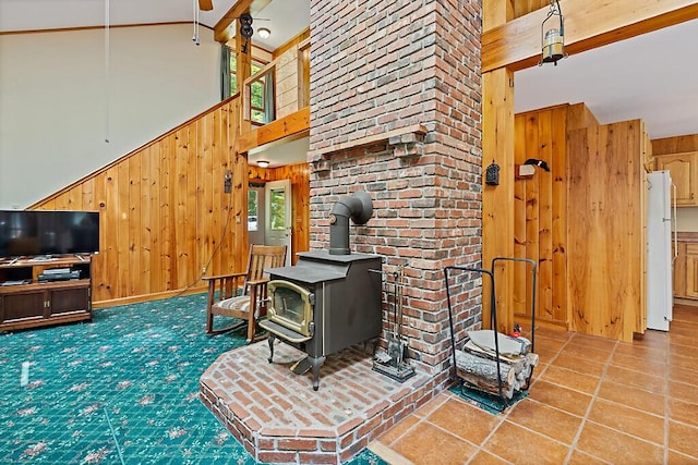 176 Perkins Beach Rd, Wayne, ME 04284 - living room with wood walls, a wood stove, high vaulted ceiling, and ceiling fan