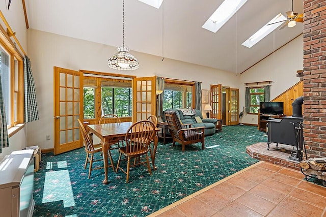 176 Perkins Beach Rd, Wayne, ME 04284 - dining room with high vaulted ceiling, a skylight, french doors, a ceiling fan, and a wood stove
