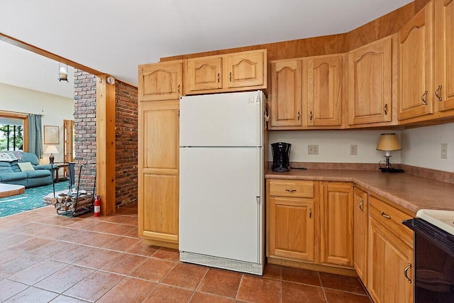 176 Perkins Beach Rd, Wayne, ME 04284 - kitchen featuring freestanding refrigerator, stove, tile patterned floors, light countertops, and brick wall