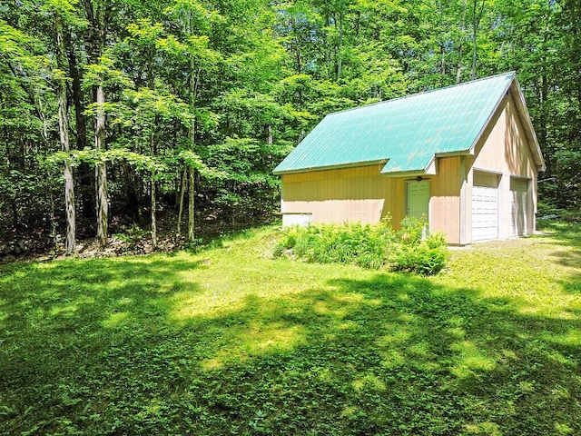 176 Perkins Beach Rd, Wayne, ME 04284 - view of green lawn featuring an outbuilding, a wooded view, and a garage