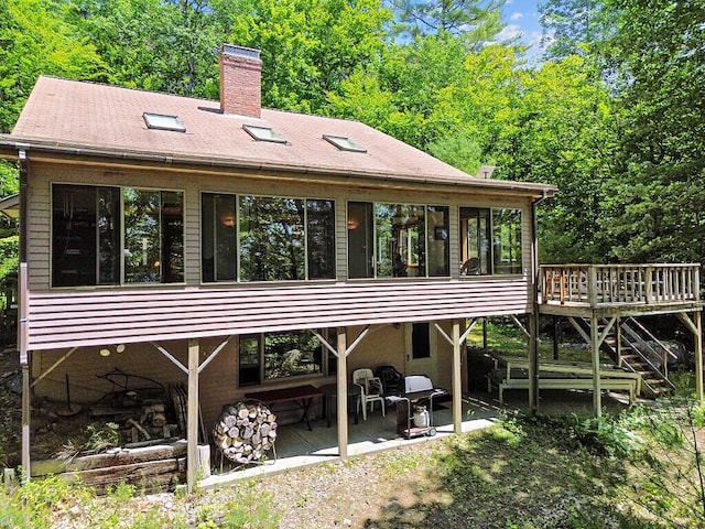 176 Perkins Beach Rd, Wayne, ME 04284 - rear view of property featuring a sunroom, a patio, a chimney, a wooden deck, and stairway
