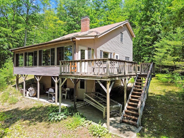 176 Perkins Beach Rd, Wayne, ME 04284 - rear view of house with a chimney, a wooden deck, stairs, a patio area, and a sunroom