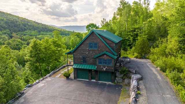 30 Hillside Dr, Kingfield, ME 04947 - view of front of house with a forest view, asphalt driveway, a garage, a metal roof, and a standing seam roof