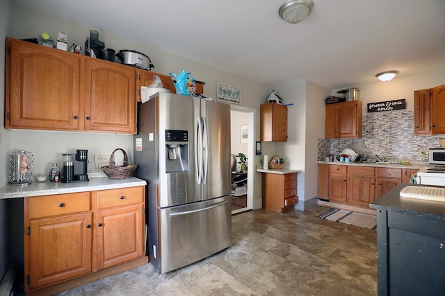 41 Dunn St, Auburn, ME 04210 - kitchen with stainless steel refrigerator with ice dispenser, backsplash, brown cabinetry, and light countertops