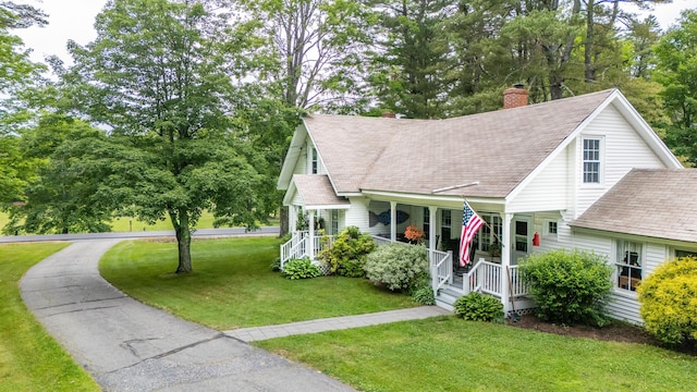 22 River Rd, Dresden, ME 04342 - view of front of home featuring covered porch, a shingled roof, a front yard, a chimney, and view of wooded area
