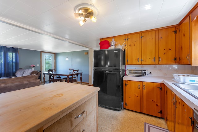 911 Spring St, Westbrook, ME 04092 - kitchen featuring freestanding refrigerator, light countertops, brown cabinetry, and tasteful backsplash