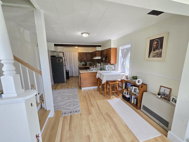 314 River Rd, Orrington, ME 04474 - kitchen featuring freestanding refrigerator, light countertops, light wood-style floors, heating unit, and a peninsula
