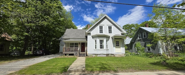 555 Depot St, Wilton, ME 04294 - view of front of property featuring covered porch, a chimney, a front yard, and roof with shingles