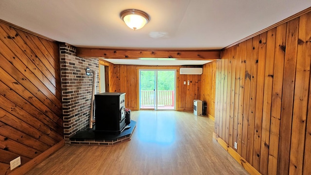1106 S Belfast Ave, Augusta, ME 04330 - unfurnished living room with a wood stove, wood finished floors, a wall unit AC, wood walls, and beam ceiling