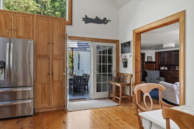 416 River Rd, Edgecomb, ME 04556 - kitchen featuring stainless steel fridge with ice dispenser, light wood-type flooring, healthy amount of natural light, vaulted ceiling, and brown cabinetry
