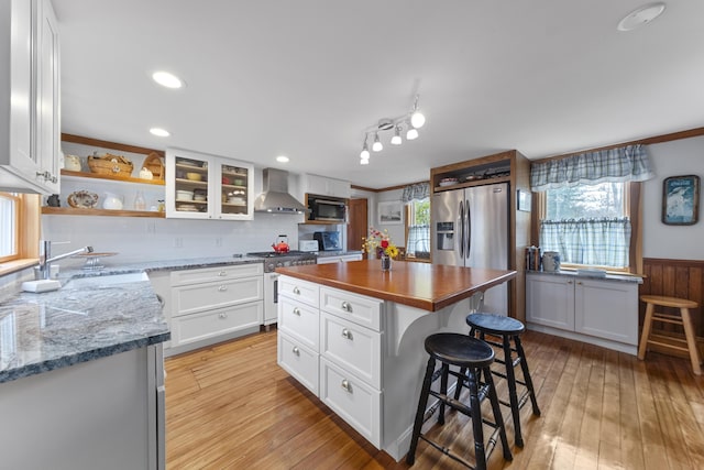 259 Mountain St, Camden, ME 04843 - kitchen with appliances with stainless steel finishes, wall chimney exhaust hood, open shelves, butcher block counters, and a breakfast bar area