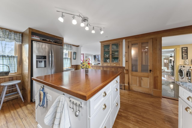 259 Mountain St, Camden, ME 04843 - kitchen featuring washer and dryer, stainless steel refrigerator with ice dispenser, light wood-style flooring, white cabinetry, and glass insert cabinets