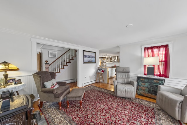 259 Mountain St, Camden, ME 04843 - living room with a baseboard heating unit, crown molding, stairs, wood finished floors, and a wainscoted wall