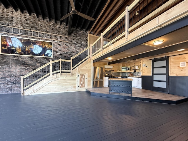 339 Main St, Calais, ME 04619 - reception area featuring a high ceiling, brick wall, wooden walls, a ceiling fan, and a barn door