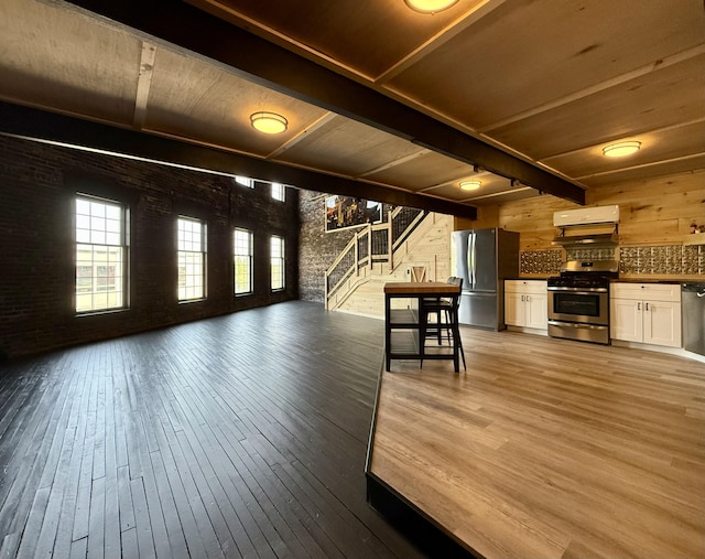 339 Main St, Calais, ME 04619 - unfurnished living room with brick wall, stairway, hardwood / wood-style flooring, a wooden ceiling with exposed beams, and wood walls