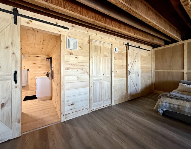 339 Main St, Calais, ME 04619 - bedroom featuring a barn door, wooden walls, and dark wood finished floors