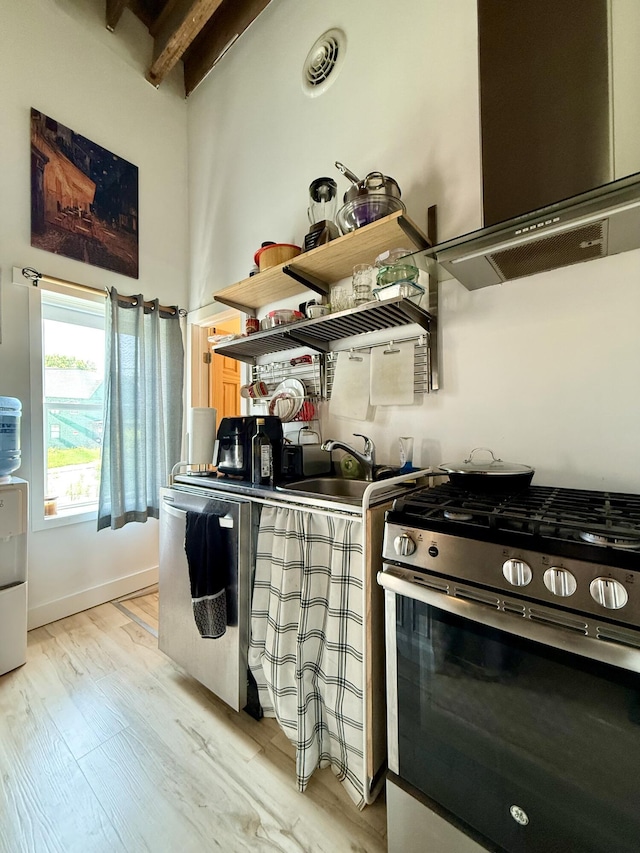 339 Main St, Calais, ME 04619 - kitchen featuring gas stove, light wood-type flooring, beamed ceiling, and range hood