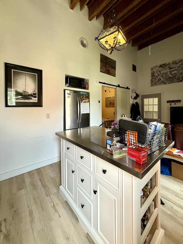 339 Main St, Calais, ME 04619 - kitchen with freestanding refrigerator, black microwave, a high ceiling, dark countertops, and beamed ceiling