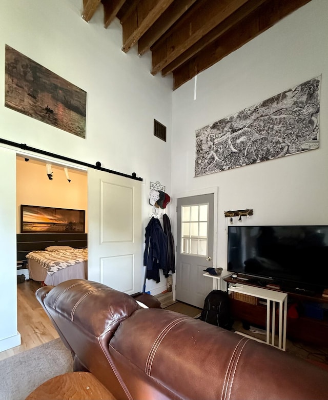 339 Main St, Calais, ME 04619 - living area featuring a barn door, a high ceiling, wood finished floors, and beamed ceiling