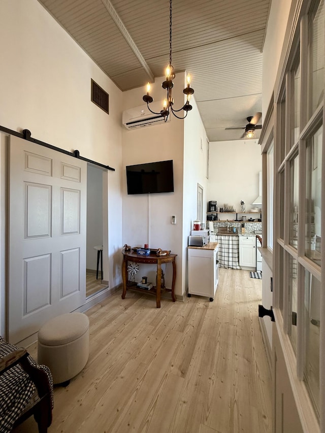 339 Main St, Calais, ME 04619 - living area with a barn door, a chandelier, light wood finished floors, ceiling fan, and a wall mounted air conditioner
