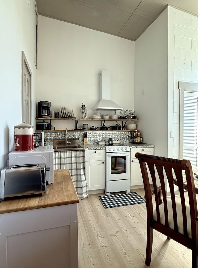 339 Main St, Calais, ME 04619 - kitchen featuring wall chimney exhaust hood, white range, light wood finished floors, white cabinetry, and light countertops