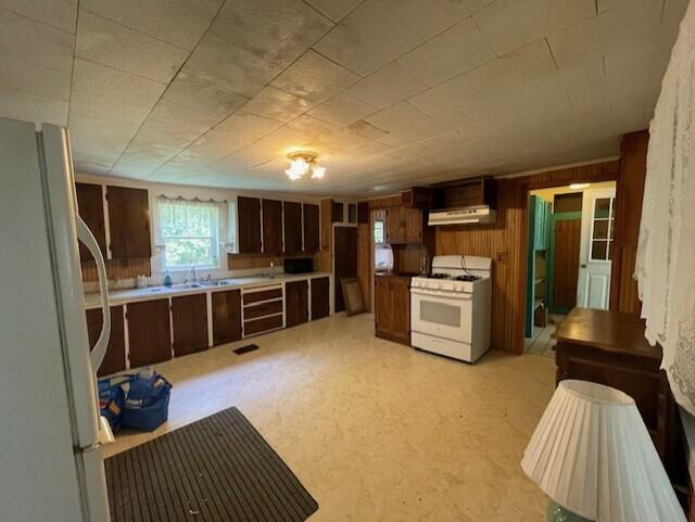 1069 Rte 193, Deblois, ME 04622 - kitchen with white appliances, under cabinet range hood, and wood walls