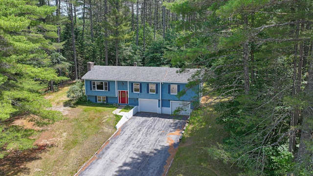 68 Hannibal Cir, Denmark, ME 04022 - split foyer home featuring a garage, driveway, a chimney, and a forest view
