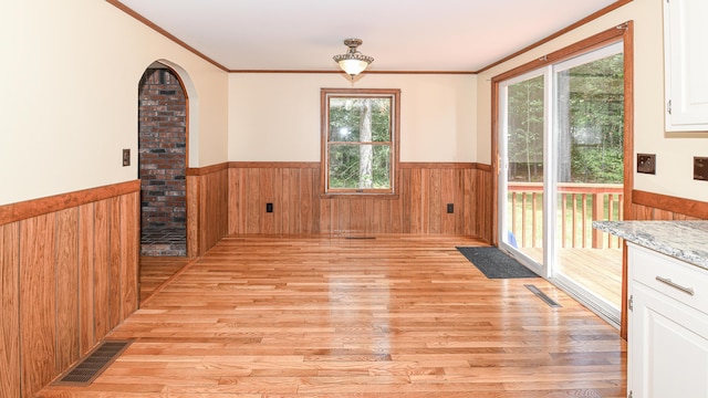68 Hannibal Cir, Denmark, ME 04022 - unfurnished dining area featuring a wainscoted wall, light wood finished floors, wood walls, crown molding, and arched walkways