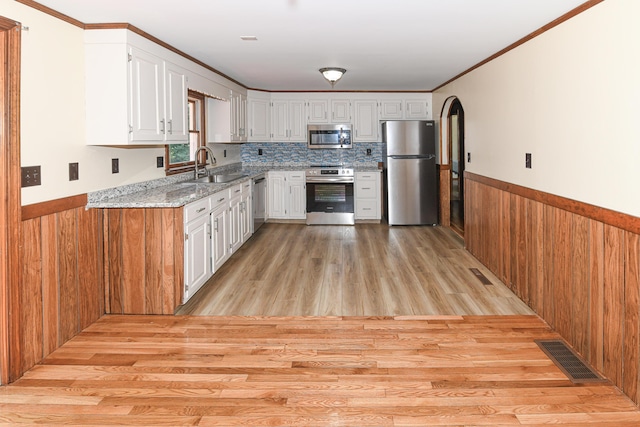 68 Hannibal Cir, Denmark, ME 04022 - kitchen with stainless steel appliances, arched walkways, light stone countertops, a wainscoted wall, and white cabinetry