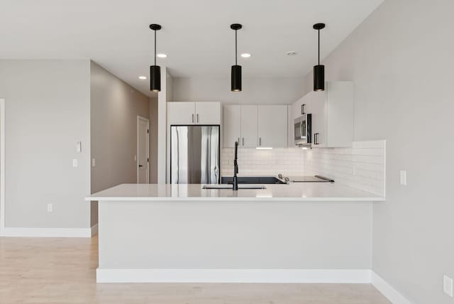 20 Upper Falls Rd Unit 403, Biddeford, ME 04005 - kitchen with stainless steel appliances, a peninsula, decorative backsplash, light wood-style flooring, and white cabinetry