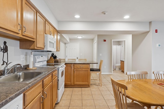 170 E Grand Ave Unit 8, Old Orchard Beach, ME 04064 - kitchen with white appliances, light tile patterned flooring, dark countertops, a peninsula, and brown cabinets