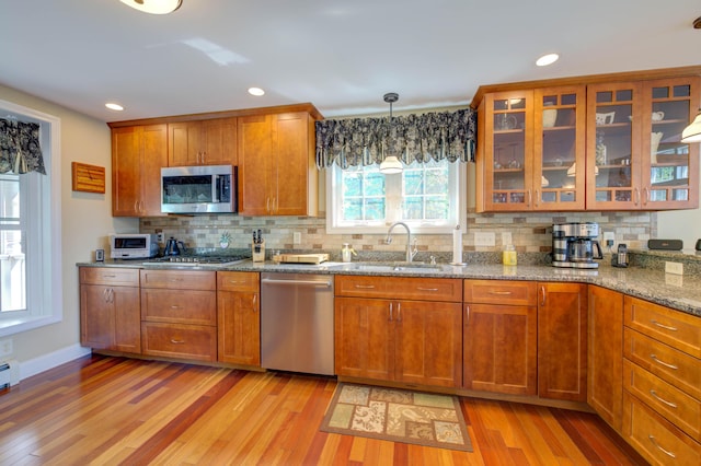 11 Washington Ct, Naples, ME 04055 - kitchen featuring appliances with stainless steel finishes, light wood-style floors, brown cabinets, stone counters, and tasteful backsplash