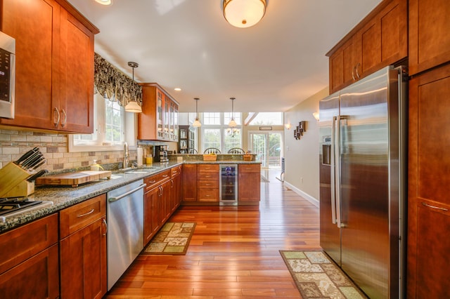 11 Washington Ct, Naples, ME 04055 - kitchen with stainless steel appliances, beverage cooler, a peninsula, light wood-type flooring, and glass insert cabinets