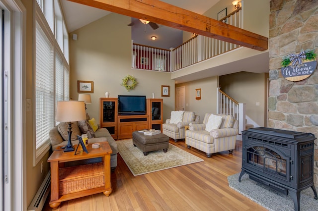 11 Washington Ct, Naples, ME 04055 - living room featuring a wood stove, stairway, high vaulted ceiling, a baseboard heating unit, and wood finished floors