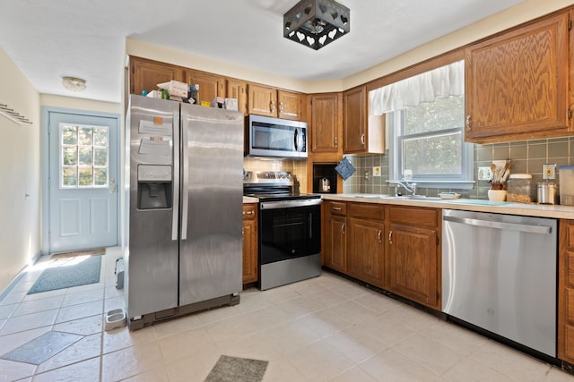 23 Laurel Pines Dr, Gorham, ME 04038 - kitchen featuring stainless steel appliances, plenty of natural light, brown cabinetry, and tasteful backsplash