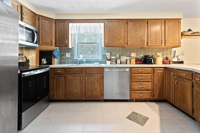 23 Laurel Pines Dr, Gorham, ME 04038 - kitchen with appliances with stainless steel finishes, tasteful backsplash, light countertops, brown cabinetry, and light tile patterned flooring