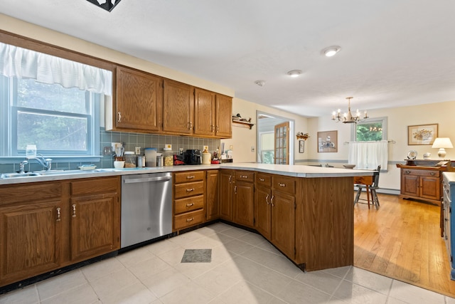 23 Laurel Pines Dr, Gorham, ME 04038 - kitchen with dishwasher, a peninsula, a chandelier, light countertops, and brown cabinetry