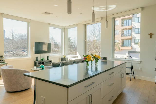 167 Newbury St Unit 206, Portland, ME 04101 - kitchen featuring plenty of natural light, light wood-style flooring, white cabinets, and decorative light fixtures