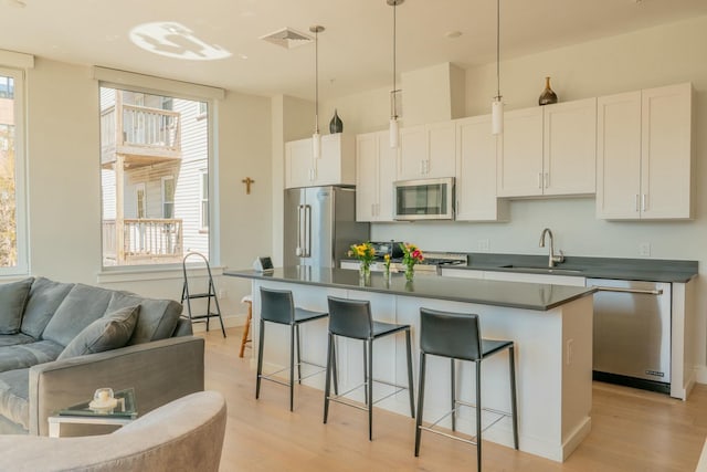 167 Newbury St Unit 206, Portland, ME 04101 - kitchen with appliances with stainless steel finishes, open floor plan, light wood-style floors, dark countertops, and a breakfast bar