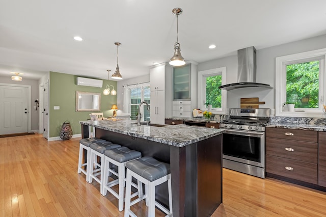 3 Ethan Way, Gray, ME 04039 - kitchen with stainless steel range with gas cooktop, wall chimney range hood, a breakfast bar area, a wall mounted air conditioner, and light wood-type flooring