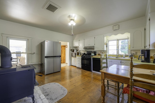 878 State Route 32, Bristol, ME 04564 - kitchen featuring stainless steel appliances, white cabinetry, under cabinet range hood, light wood-style flooring, and a desk
