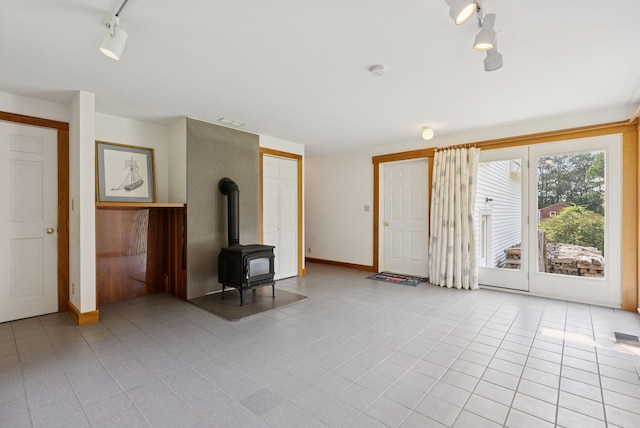 428 Webbs Mills Rd, Raymond, ME 04071 - empty room featuring rail lighting, a wood stove, light tile patterned floors, and a smoke detector