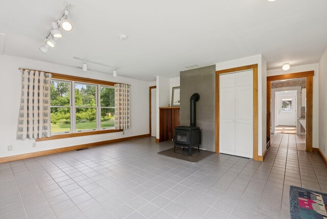 428 Webbs Mills Rd, Raymond, ME 04071 - unfurnished living room with rail lighting, light tile patterned flooring, and a wood stove