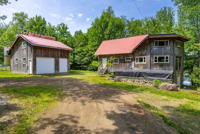 22 Woodpecker Ln, Embden, ME 04958 - view of front of property with a garage, an outbuilding, and a metal roof